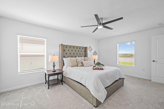 bedroom with a ceiling fan, light carpet, a textured ceiling, and baseboards