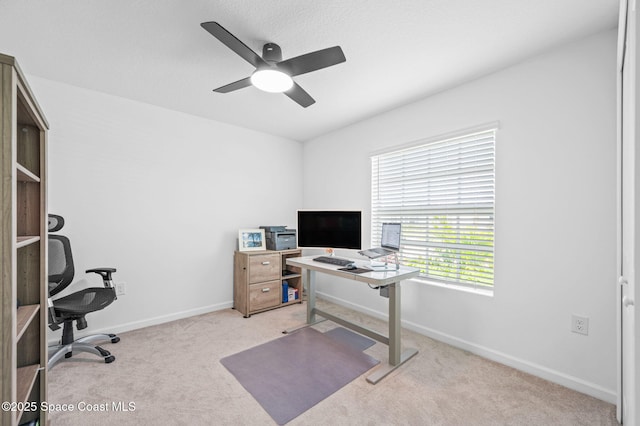 office space with light carpet, a ceiling fan, and baseboards