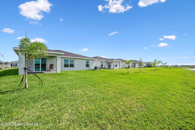 rear view of property with a lawn and stucco siding