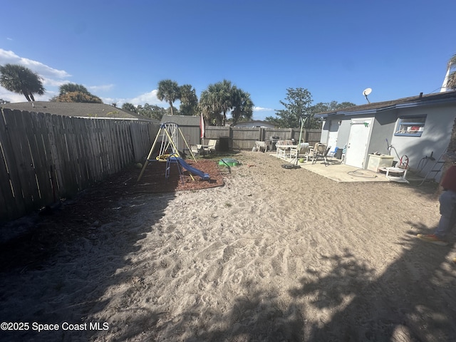 view of yard featuring a patio area, a playground, and a fenced backyard