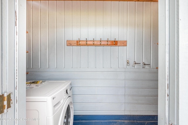 clothes washing area featuring laundry area, washer / clothes dryer, and wood walls