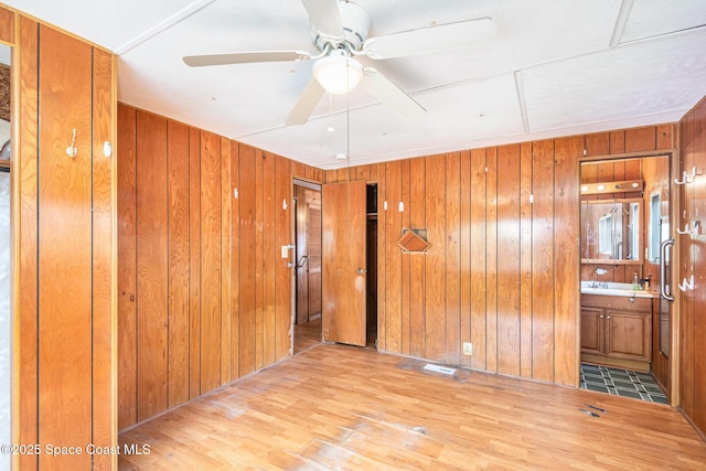 spare room with a ceiling fan, wood walls, and wood finished floors