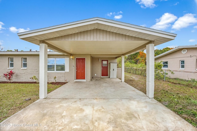 view of front of house featuring driveway, fence, a carport, and a front yard