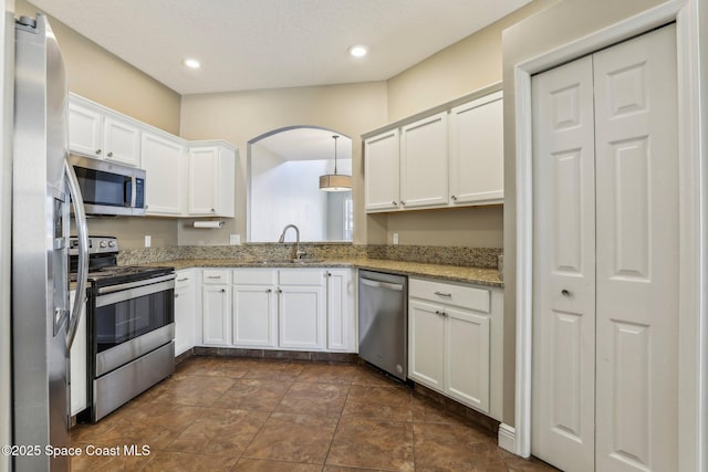 kitchen featuring recessed lighting, stainless steel appliances, a sink, white cabinetry, and light stone countertops