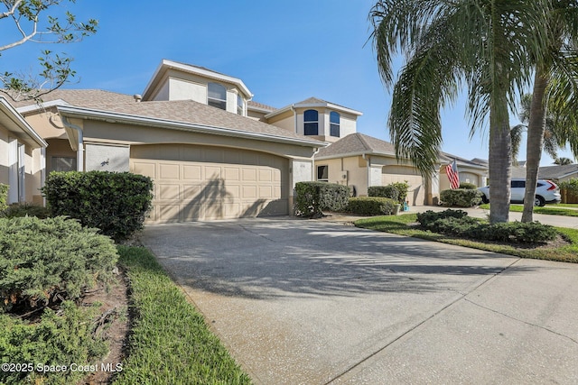 view of front facade featuring concrete driveway, an attached garage, and stucco siding