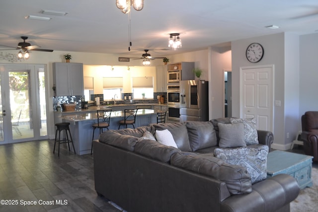 living area with visible vents, a ceiling fan, and dark wood-style flooring