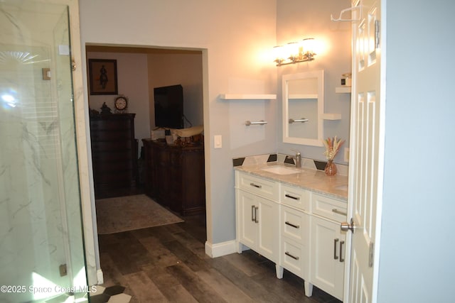 bathroom with a marble finish shower, wood finished floors, and vanity