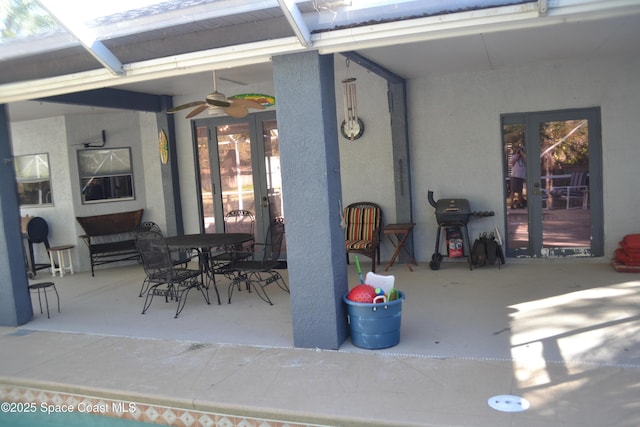 view of patio / terrace featuring outdoor dining space, glass enclosure, french doors, and a ceiling fan