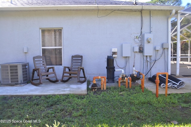 rear view of house with cooling unit, a patio area, roof with shingles, and stucco siding