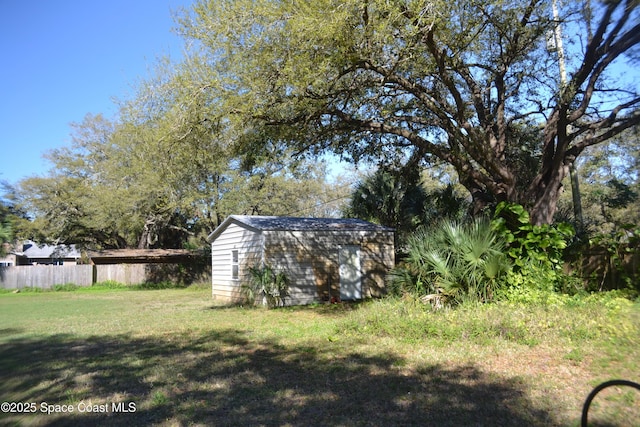 view of yard featuring a storage unit, an outbuilding, and fence