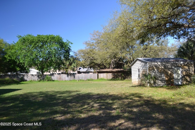 view of yard featuring a storage unit, an outbuilding, and fence