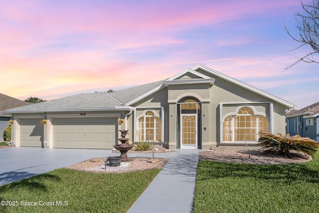 ranch-style home with a garage, driveway, a lawn, and stucco siding