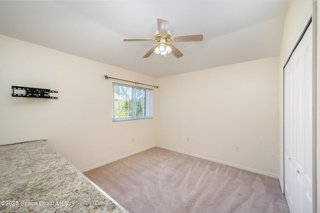 bedroom featuring light carpet, a ceiling fan, baseboards, and a closet