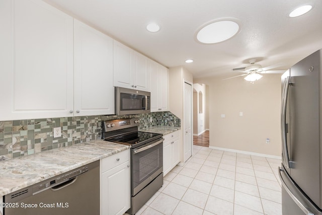 kitchen featuring appliances with stainless steel finishes, backsplash, white cabinetry, and a ceiling fan