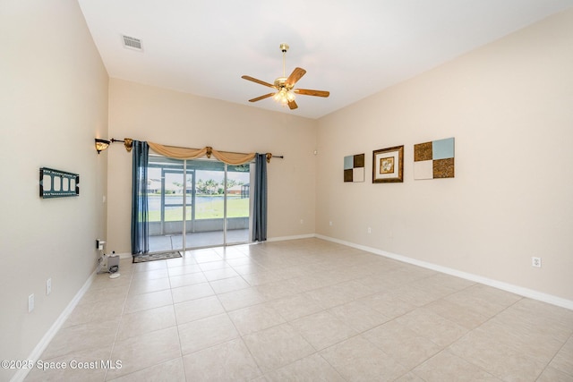 empty room with ceiling fan, light tile patterned floors, visible vents, and baseboards