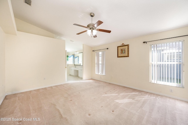 spare room featuring ceiling fan, lofted ceiling, light carpet, visible vents, and baseboards