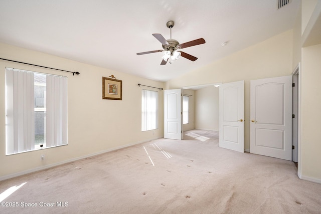 unfurnished bedroom with lofted ceiling, multiple windows, light carpet, and visible vents