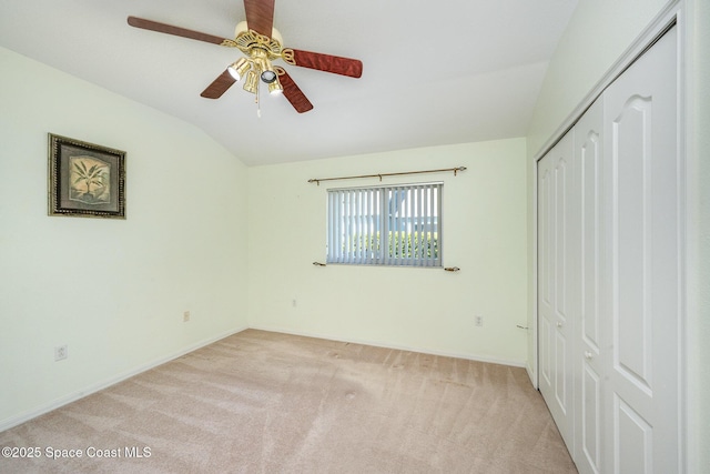 unfurnished bedroom featuring baseboards, light colored carpet, lofted ceiling, ceiling fan, and a closet