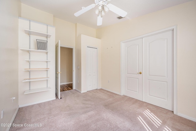 unfurnished bedroom featuring baseboards, ceiling fan, visible vents, and light colored carpet