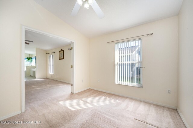 spare room featuring light carpet, ceiling fan, baseboards, and vaulted ceiling