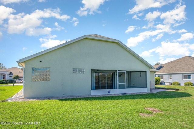 back of house with a yard, a sunroom, and stucco siding