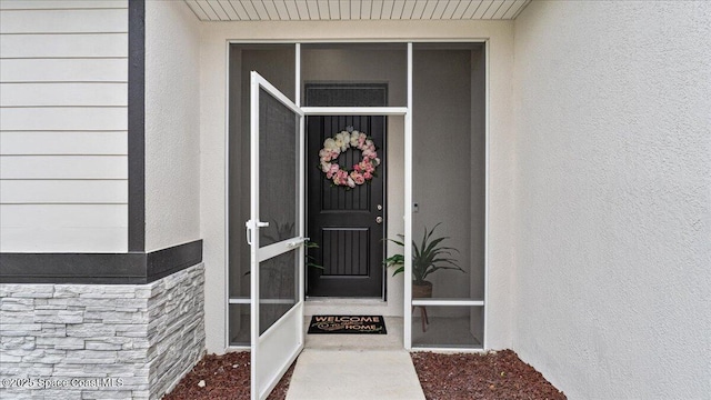 doorway to property featuring stone siding and stucco siding