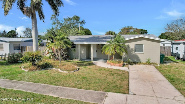 view of front of property with a front lawn, roof with shingles, and fence