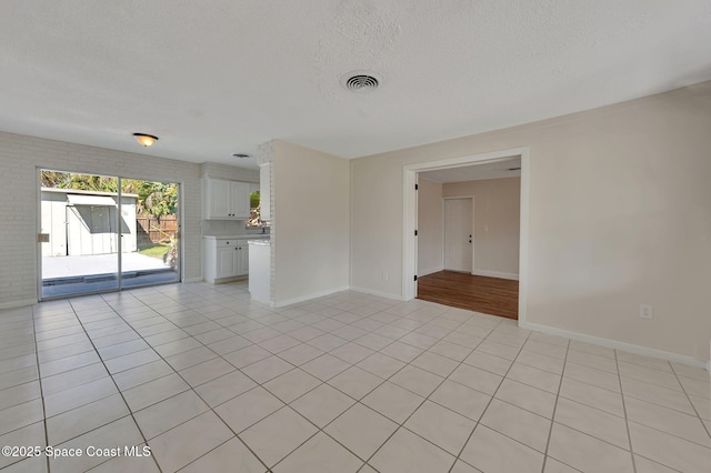 unfurnished room featuring baseboards, visible vents, a textured ceiling, and light tile patterned flooring