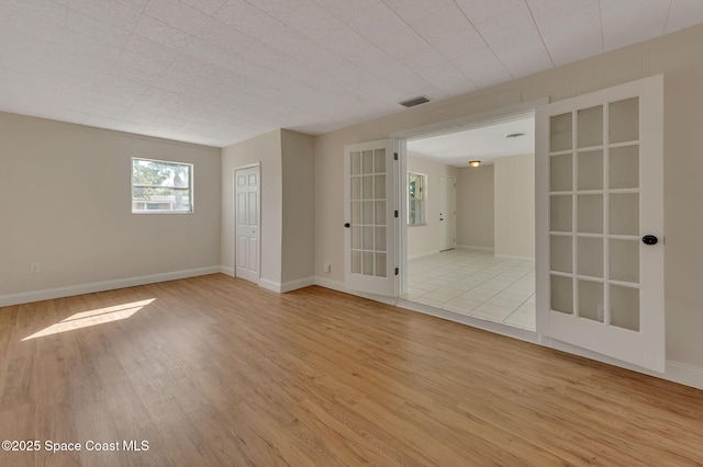 empty room featuring visible vents, baseboards, and wood finished floors