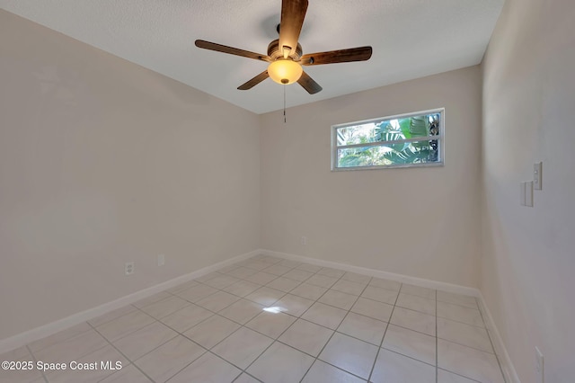 empty room featuring ceiling fan, a textured ceiling, light tile patterned flooring, and baseboards