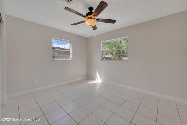 spare room with a textured ceiling, visible vents, a ceiling fan, and baseboards