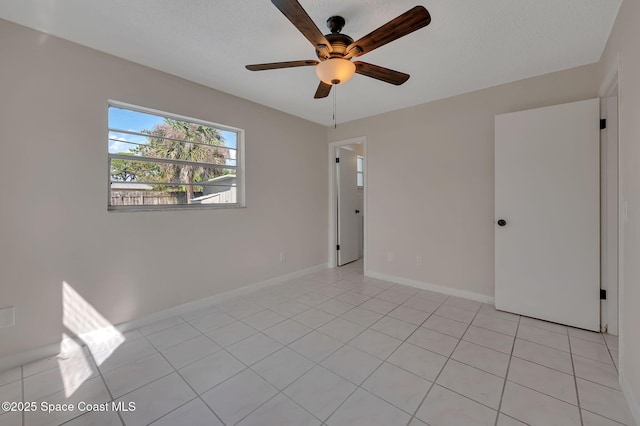 unfurnished room featuring light tile patterned floors, ceiling fan, baseboards, and a textured ceiling