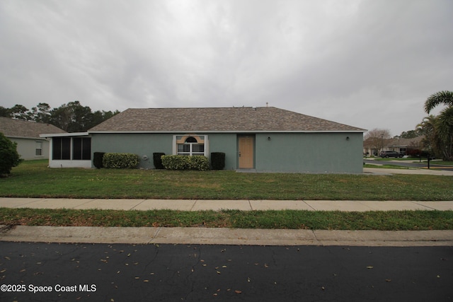 ranch-style house featuring a front yard, a sunroom, and stucco siding