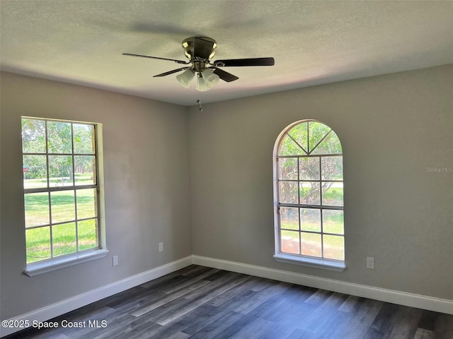 unfurnished room featuring a textured ceiling, ceiling fan, dark wood finished floors, and baseboards