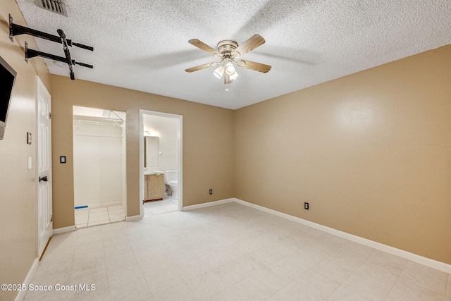 empty room with a ceiling fan, visible vents, a textured ceiling, and baseboards