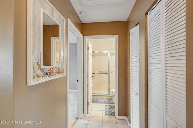 hallway featuring a textured ceiling and light tile patterned flooring