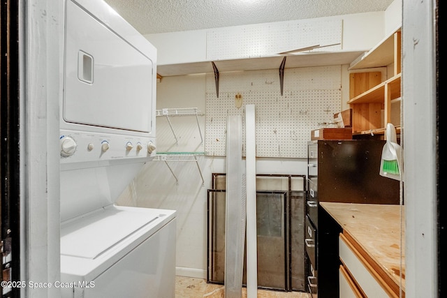 washroom with laundry area, a textured ceiling, and stacked washing maching and dryer