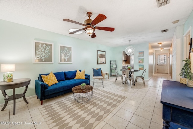 living area featuring light tile patterned floors, visible vents, a textured ceiling, and ceiling fan with notable chandelier