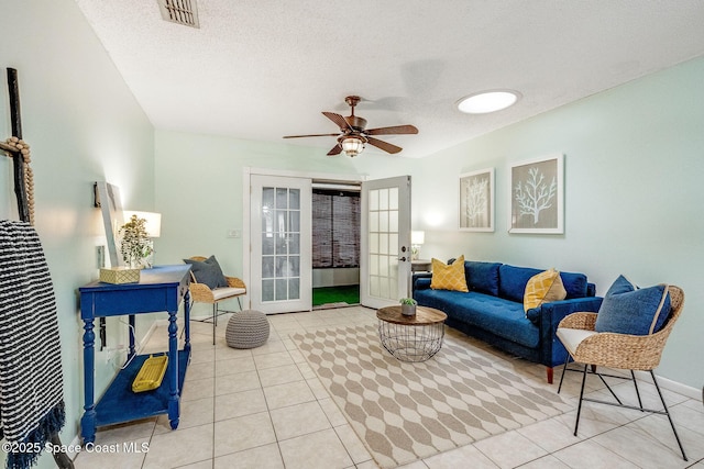 living area with french doors, visible vents, light tile patterned flooring, ceiling fan, and a textured ceiling