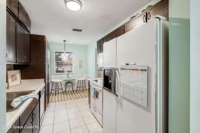 kitchen with light tile patterned floors, white appliances, visible vents, hanging light fixtures, and light countertops