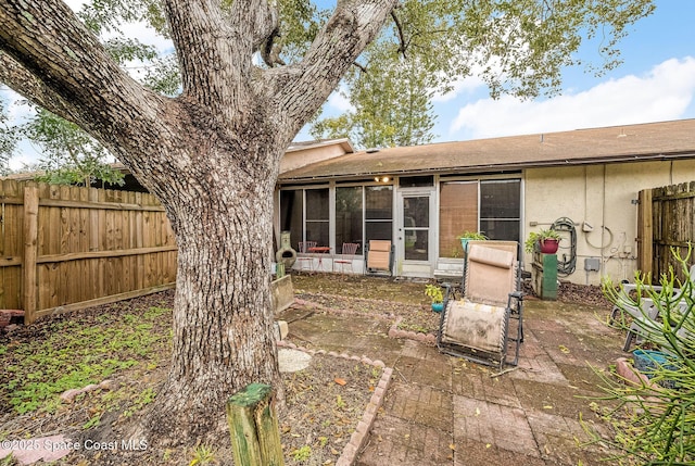 back of property featuring a sunroom, fence, stucco siding, and a patio