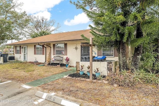 view of front of home featuring a front lawn, cooling unit, and stucco siding