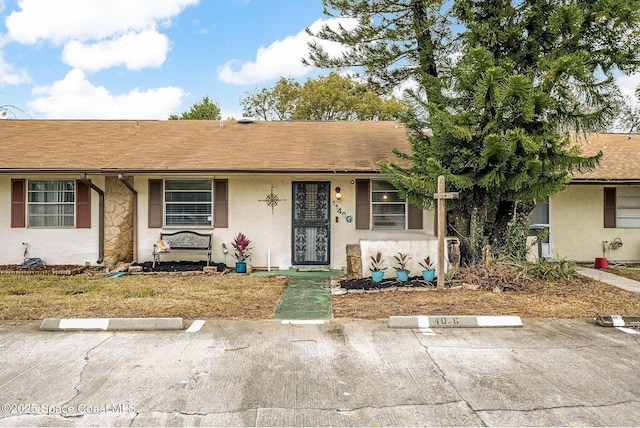 single story home with uncovered parking, a shingled roof, and stucco siding