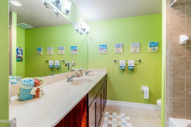 bathroom featuring double vanity, toilet, a sink, tile patterned flooring, and baseboards