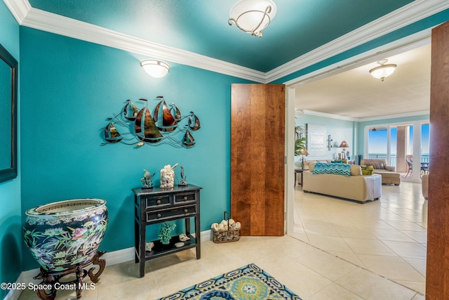 hallway with light tile patterned floors, ornamental molding, and baseboards