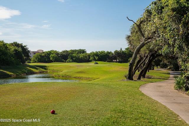 view of property's community with view of golf course, a yard, and a water view