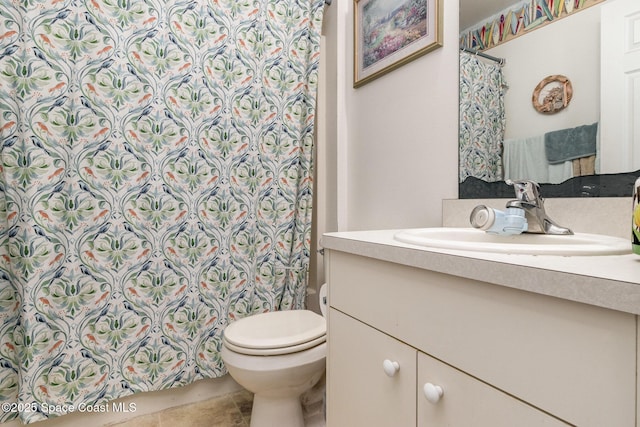 bathroom featuring tile patterned flooring, curtained shower, vanity, and toilet