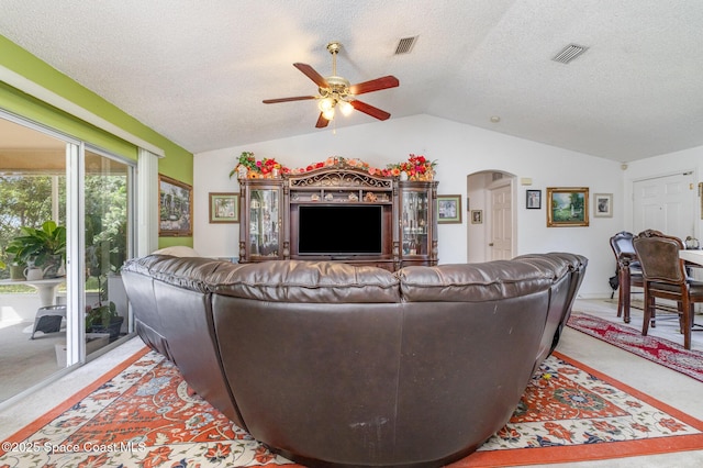 living area with arched walkways, vaulted ceiling, visible vents, and light colored carpet