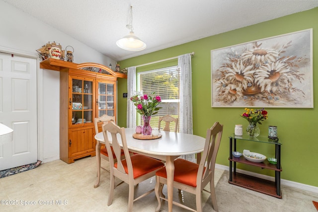 dining area with a textured ceiling, vaulted ceiling, and baseboards