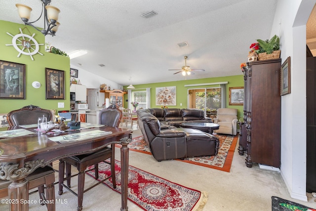 dining area with visible vents, light colored carpet, lofted ceiling, a textured ceiling, and ceiling fan with notable chandelier